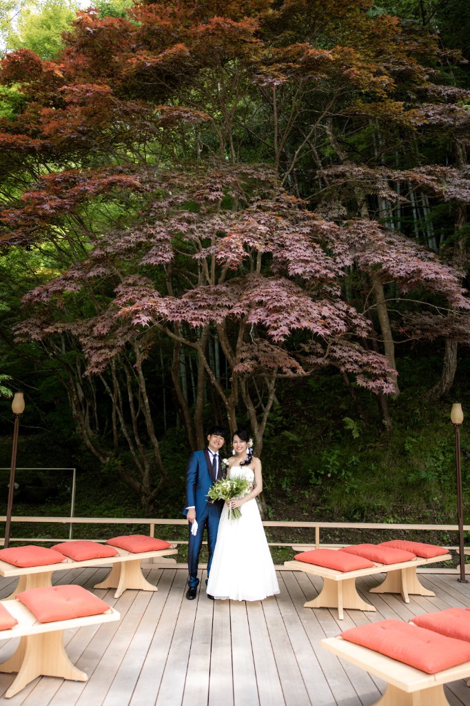 紅葉の前に立つドレス姿の新郎新婦