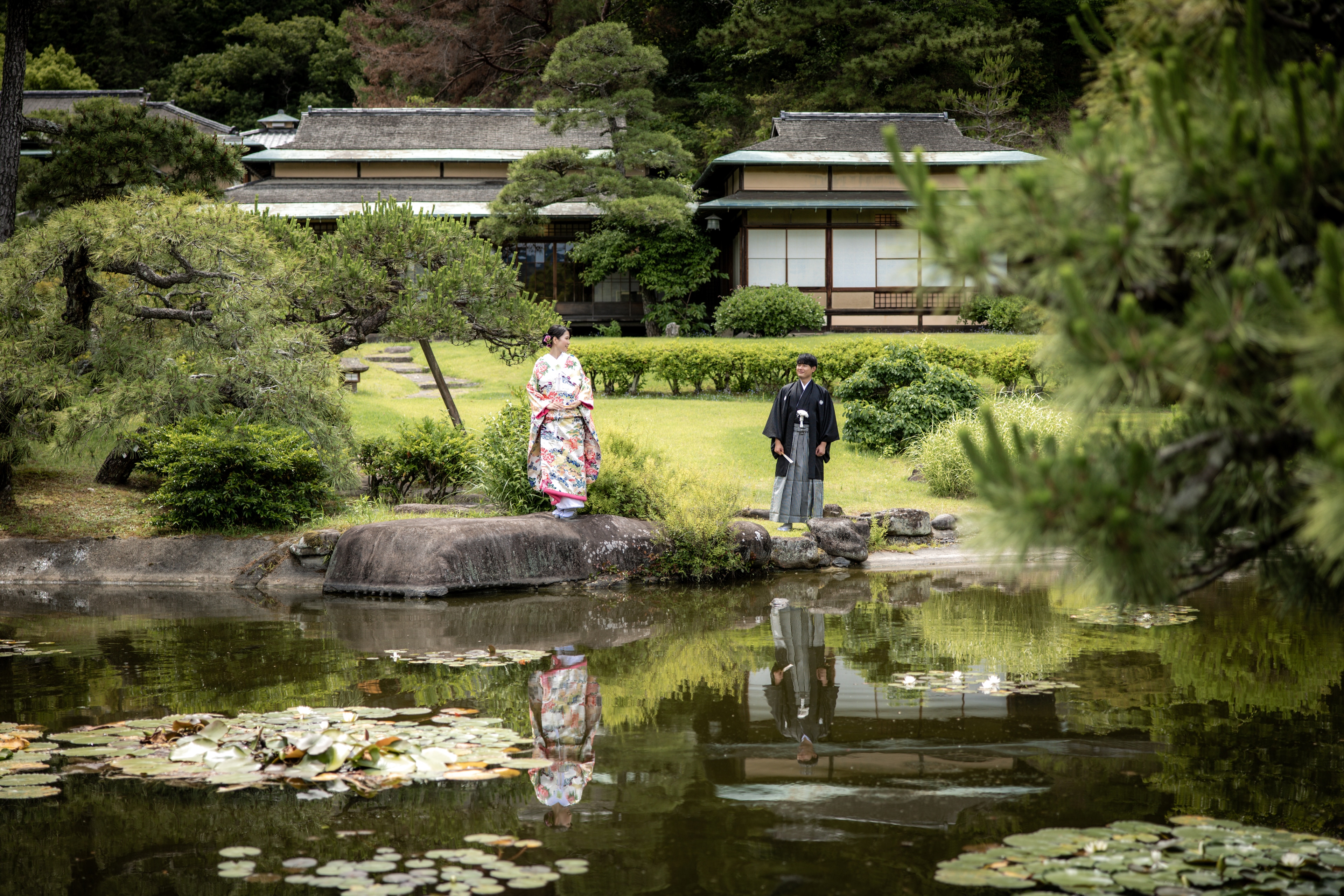 三養荘の池泉庭園と和装の新郎新婦