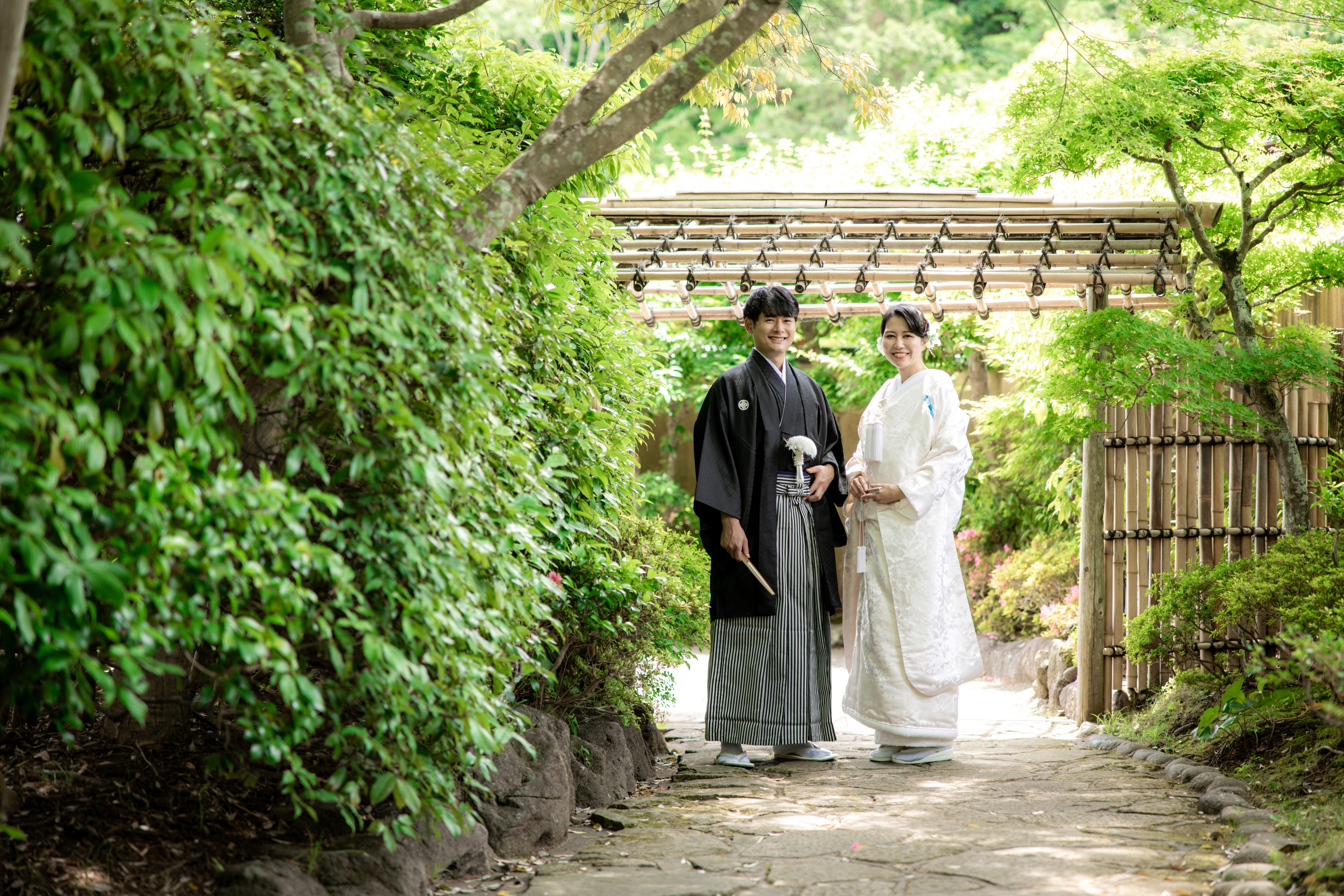 緑に包まれた石畳を歩く白無垢の新郎新婦