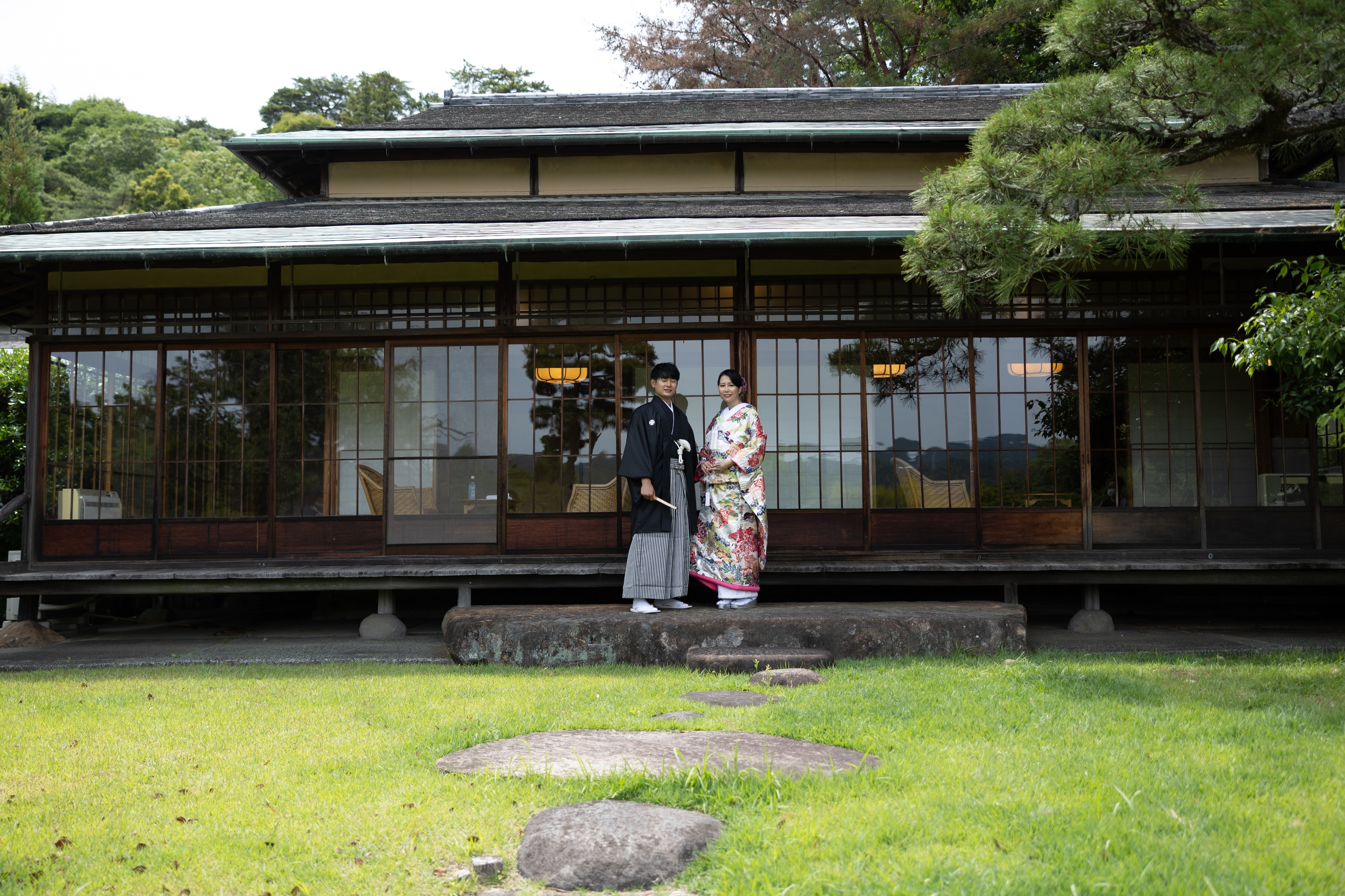 三養荘の縁側に立つ和装の新郎新婦